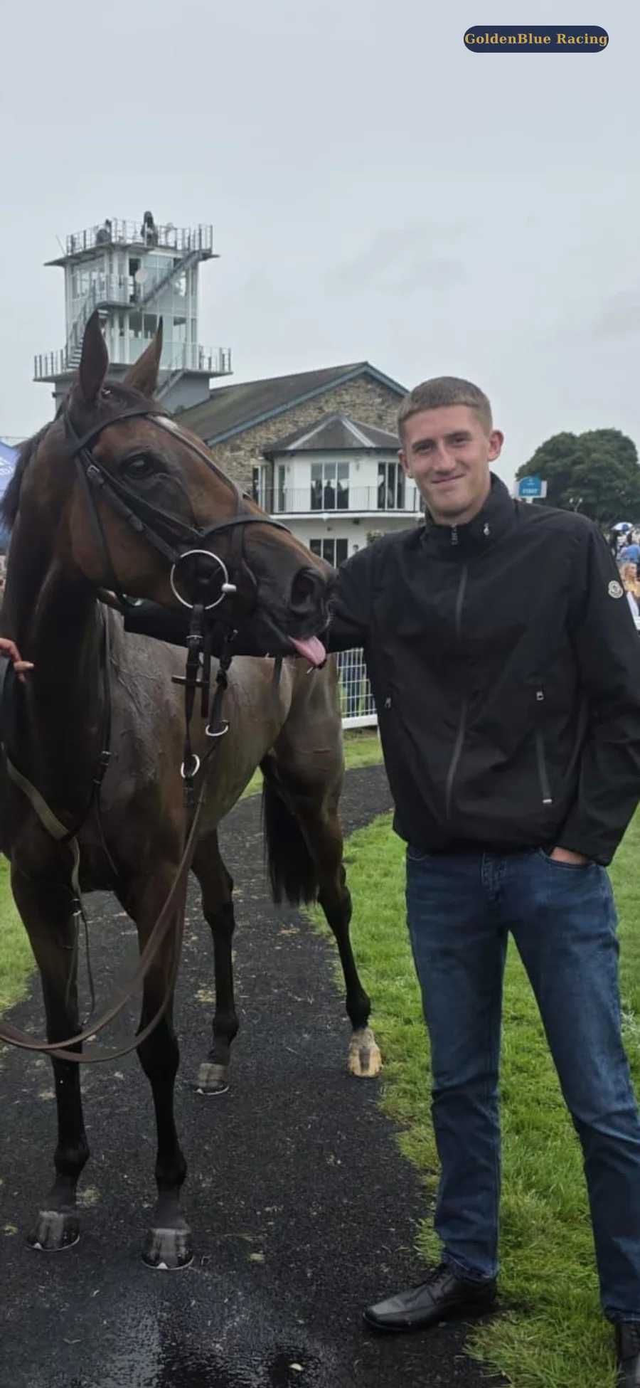 GoldenBlue team member standing beside a playful racehorse in the parade ring